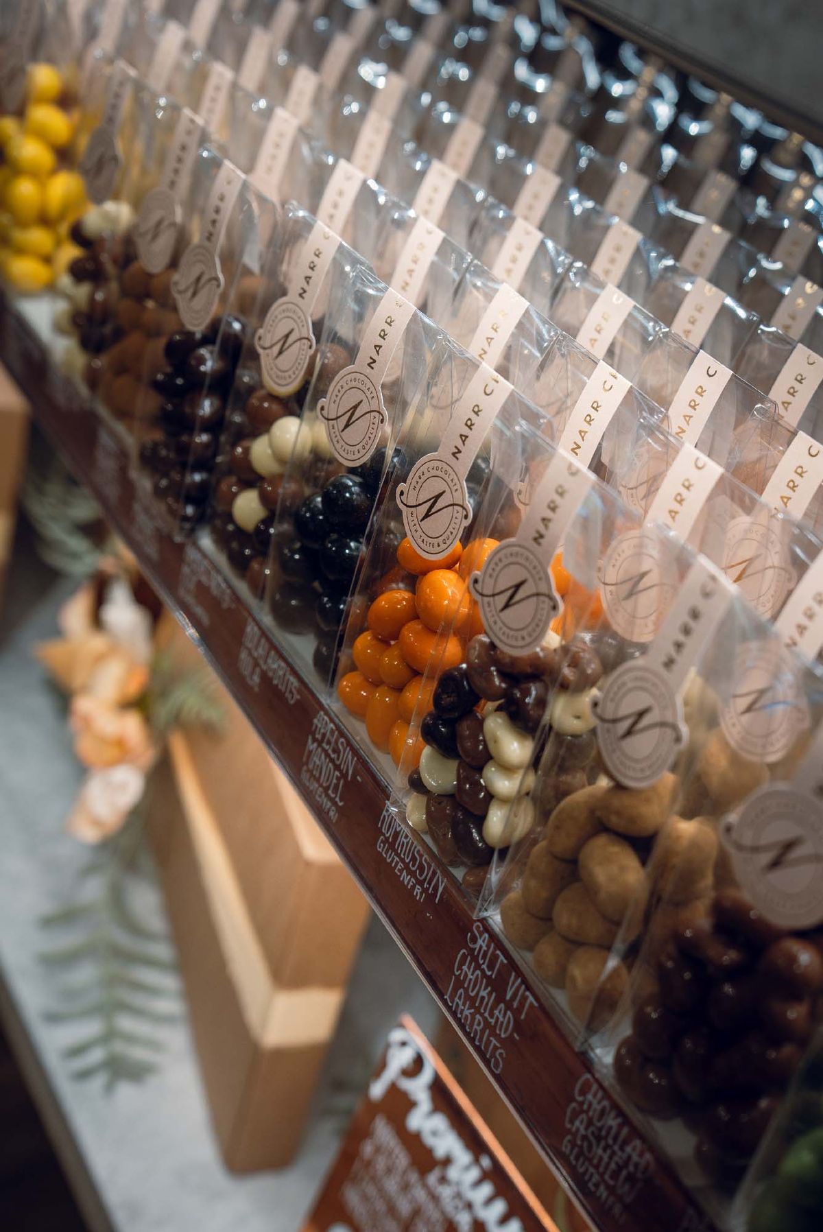 Påsar med chokladdragerade nötter och godis från Narr Chocolate uppställda i butik.