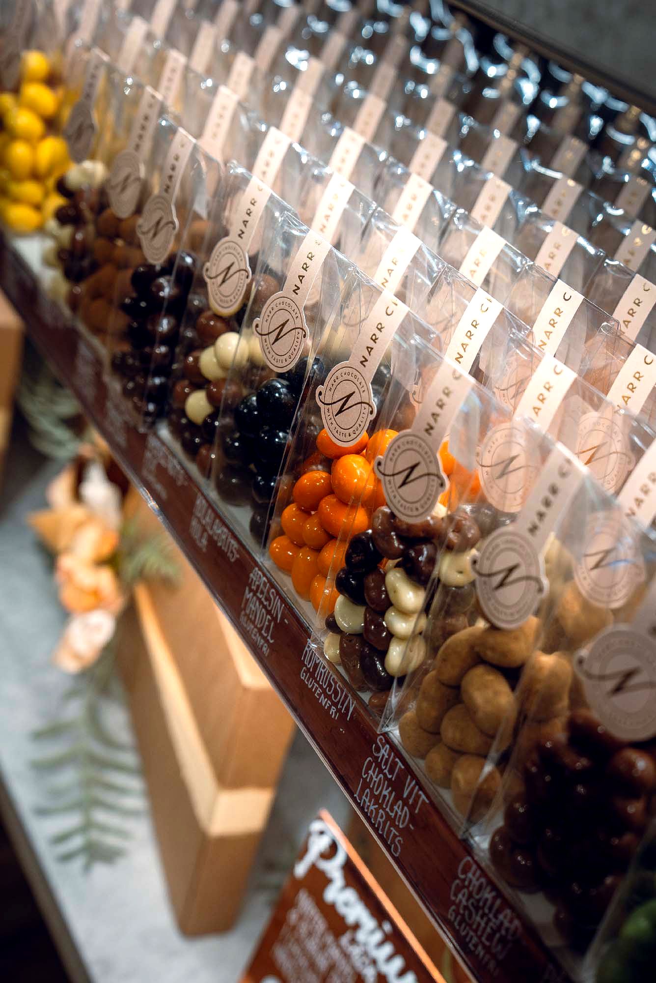 Påsar med chokladdragerade nötter och godis från Narr Chocolate uppställda i butik.