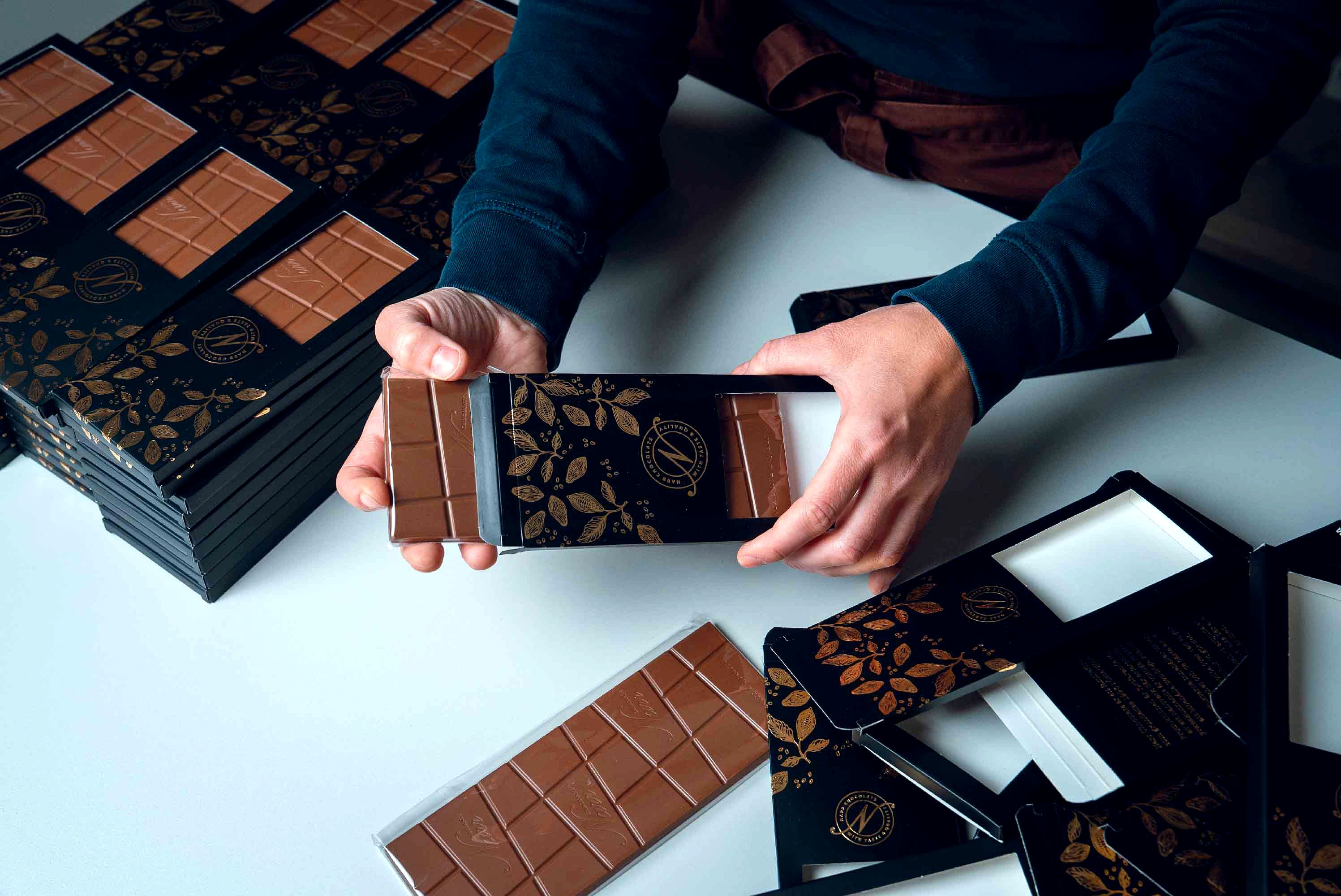 Chokladkakor packas för hand i svarta och guldfärgade förpackningar från Narr Chocolate.