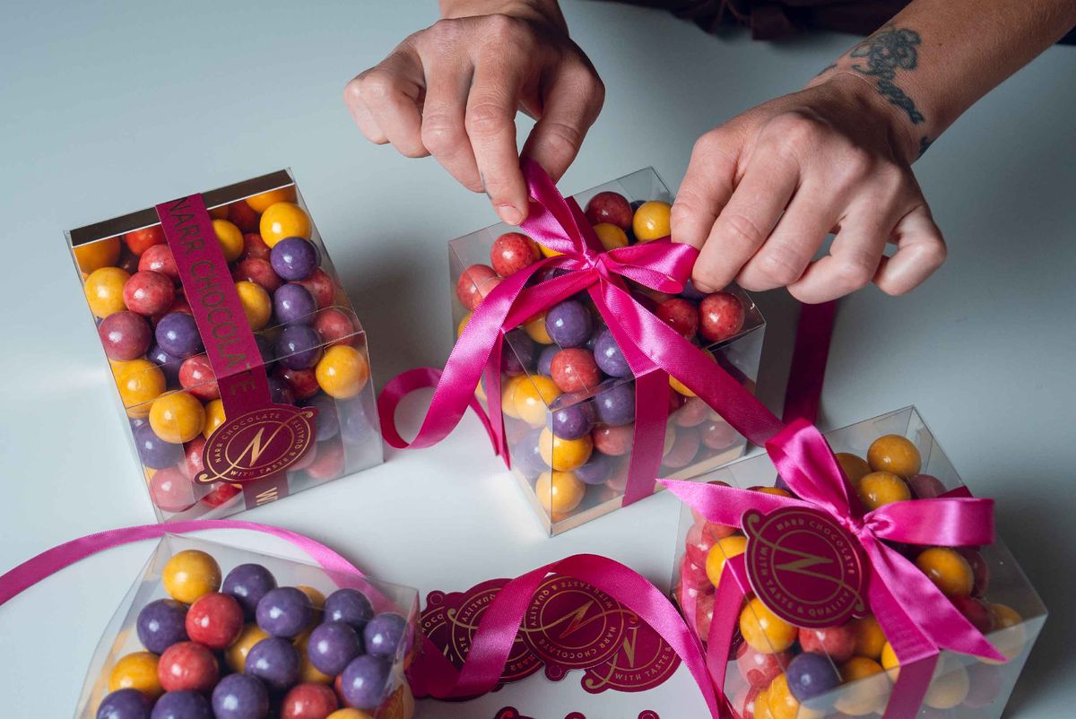 Presentask med färgglada chokladkulor från Narr Chocolate knyts med ett rosa sidenband.