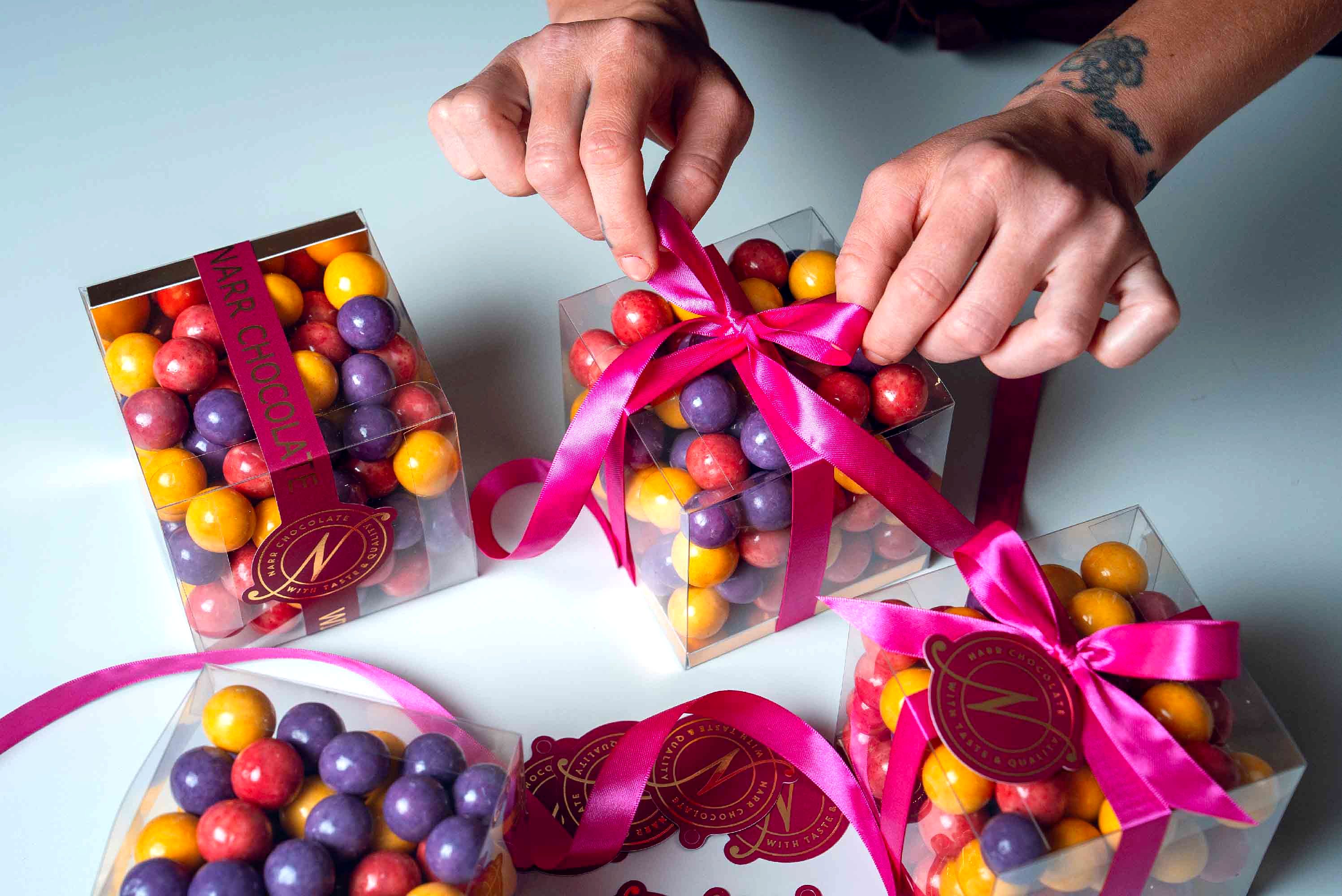 Presentask med färgglada chokladkulor från Narr Chocolate knyts med ett rosa sidenband.